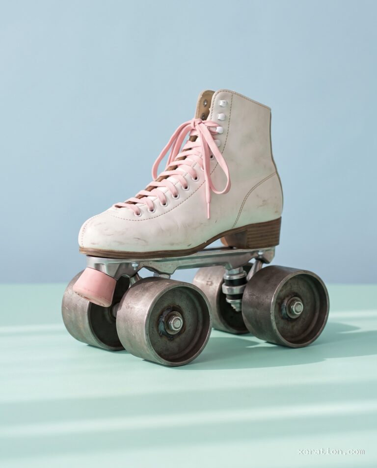 White leather roller skate with pink laces resting on heavy cylindrical steel road-roller drums against a pastel wall.